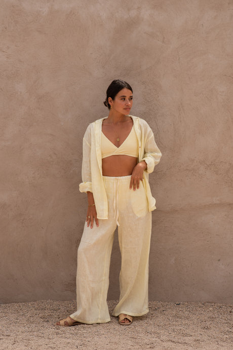 Model wearing yellow Limone linen resort wear with wide leg pants, shirt, and bikini top